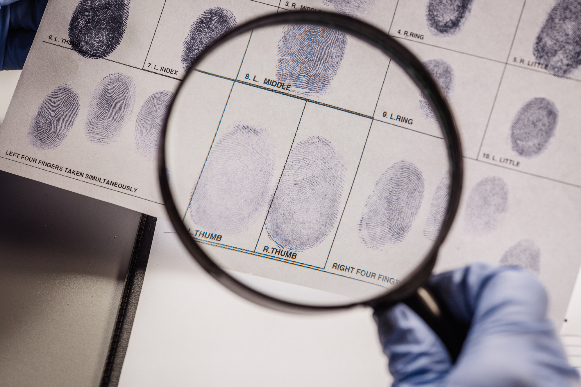 Detective through a magnifying glass looking at a fingerprint